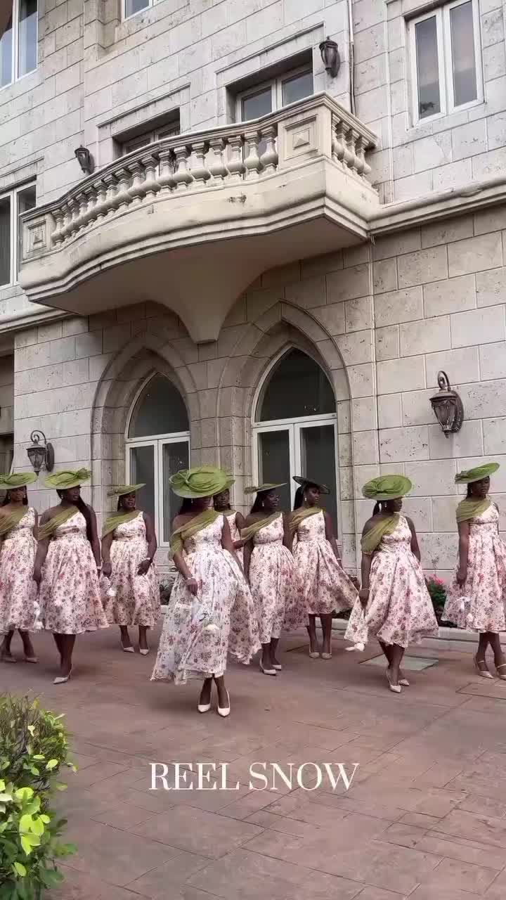 This may contain: a group of women in dresses and hats walking down the street