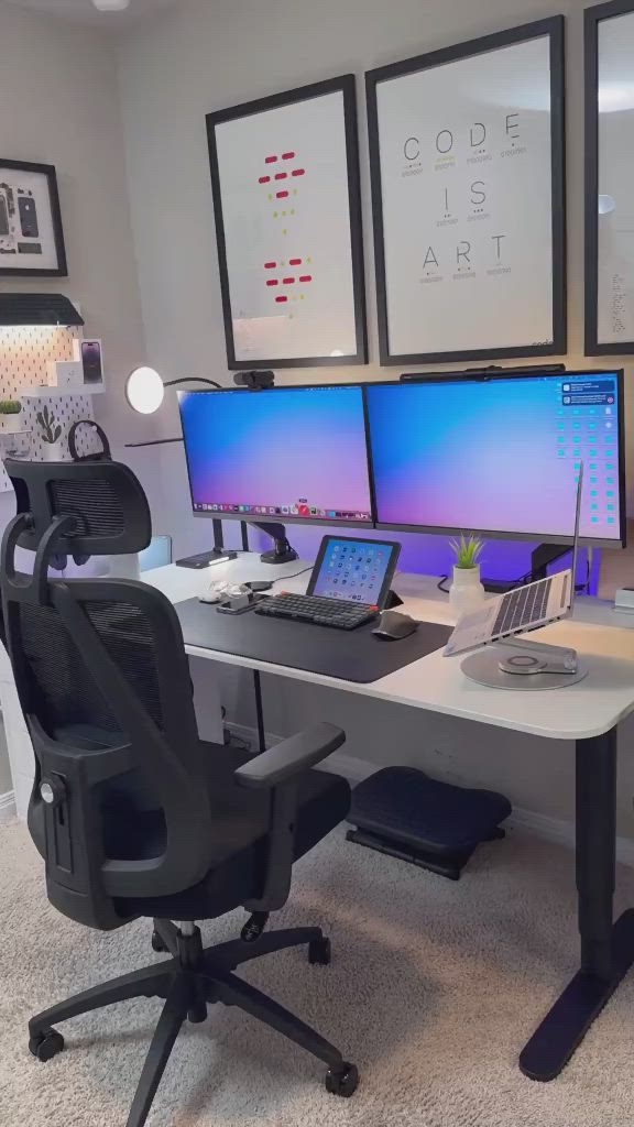 This may contain: a desk with two computer monitors and a laptop on it in front of some pictures