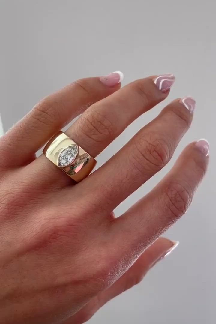 This may contain: a woman's hand with pink manicured nails and a gold ring