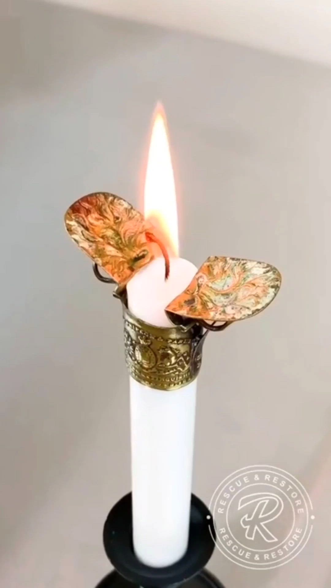 This may contain: a white candle with a butterfly decoration on it's side and a lit candle in the middle