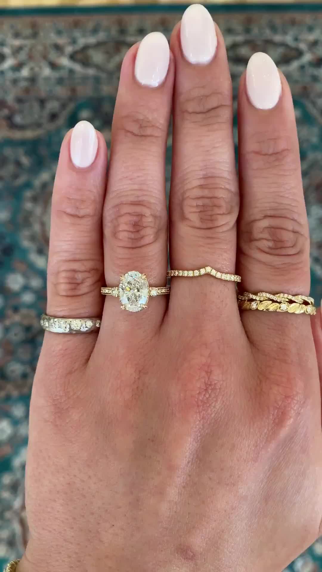 This may contain: a woman's hand with three different rings on her fingers and one ring in the middle