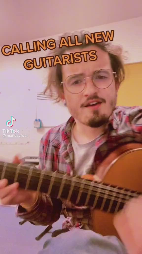 This may contain: a man with glasses playing a guitar in front of a tv screen that says calling all new guitarists