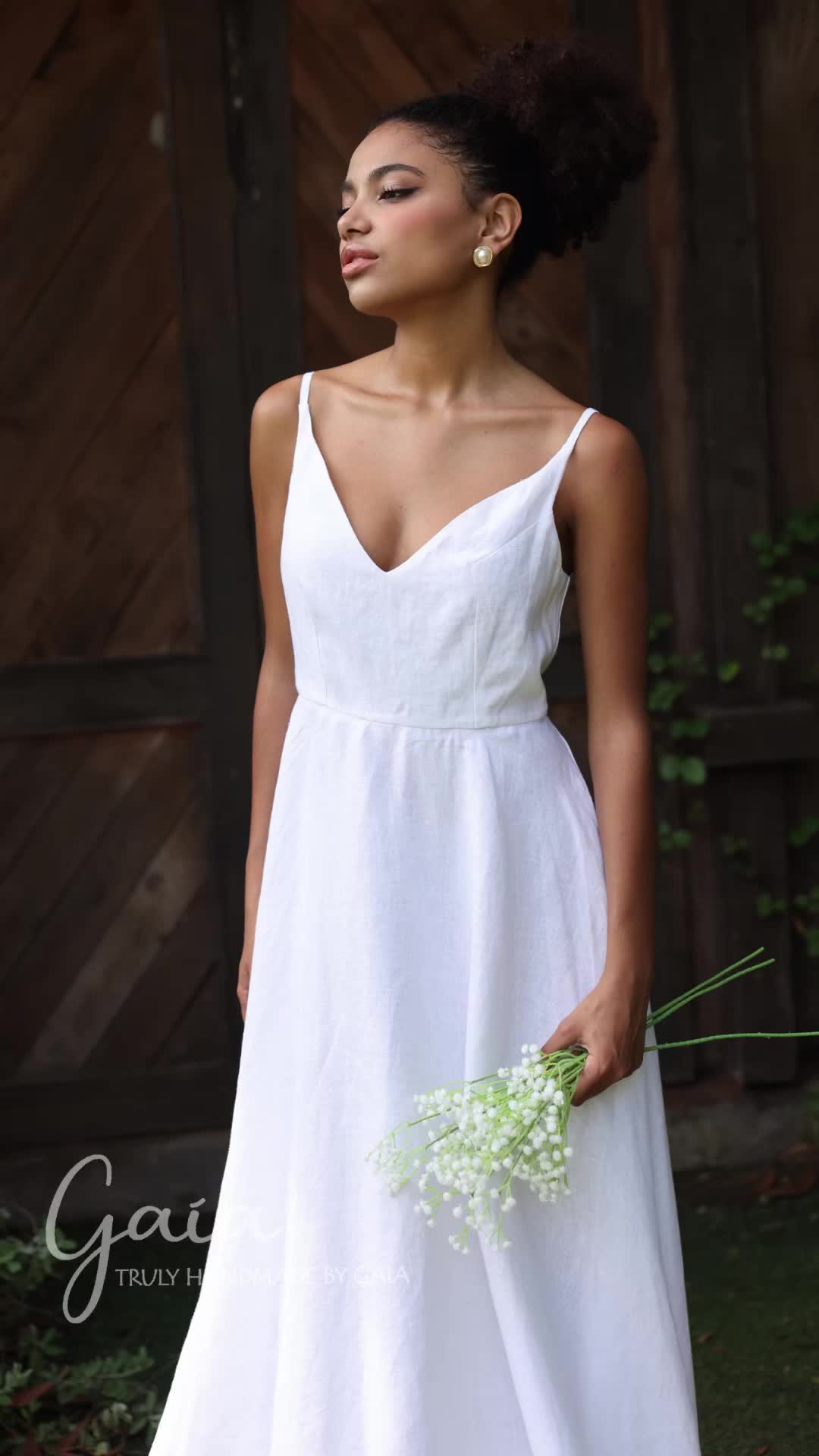 This may contain: a woman in a white dress holding flowers