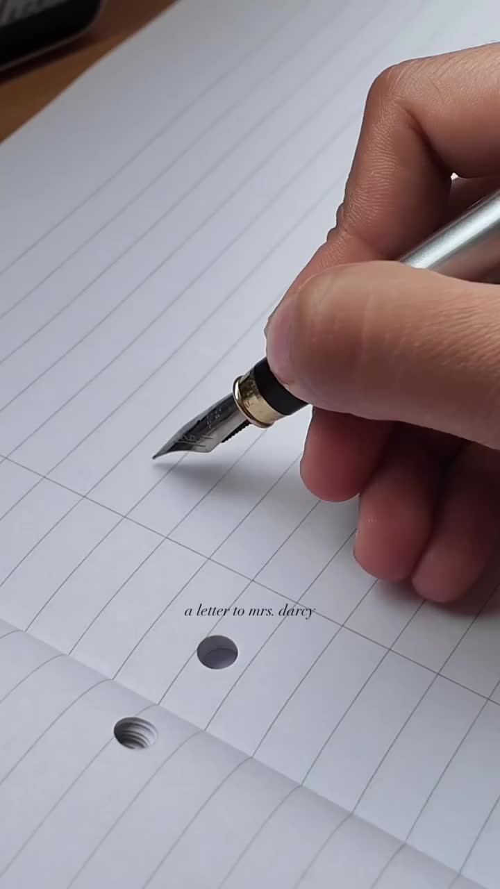 This may contain: two fountain pens sitting on top of a piece of paper that has writing on it