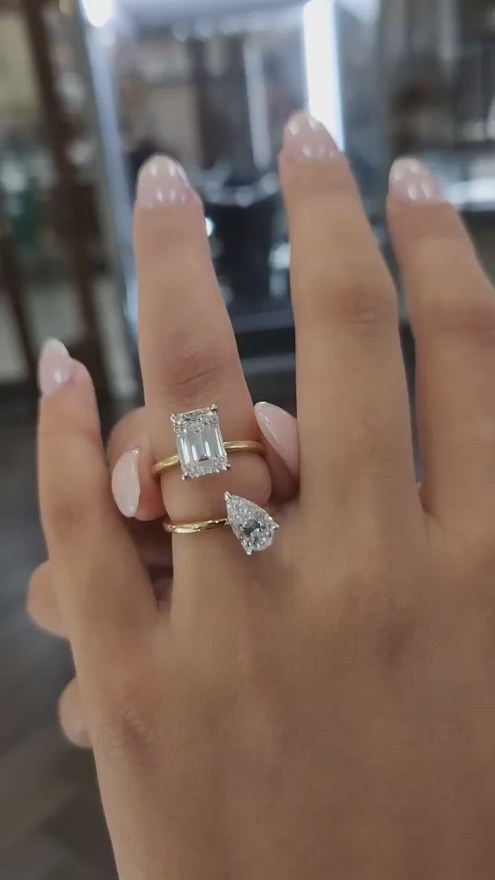 This may contain: a close up of a person's hand with a ring on their finger and two diamonds in the middle