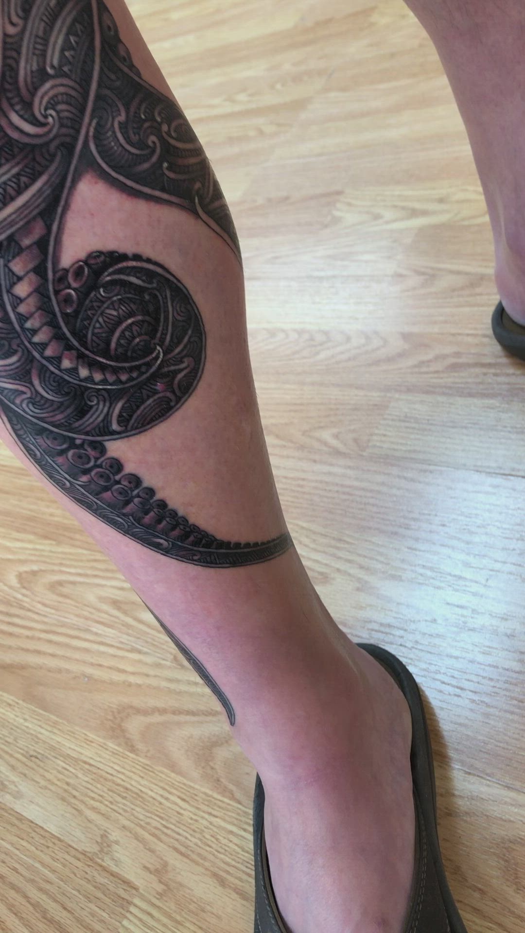 This may contain: a man's leg with an intricate tattoo on it, and his shoes are black