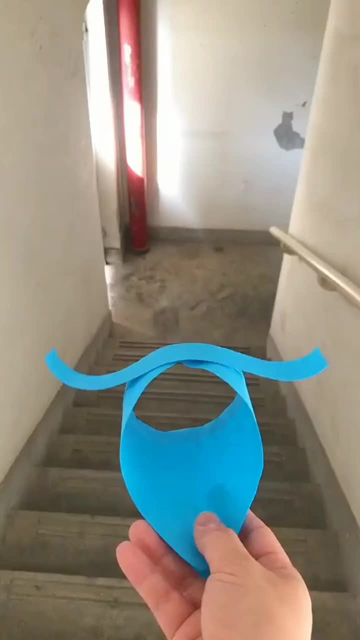 This may contain: a hand holding a blue object in front of stairs with an apple logo on it