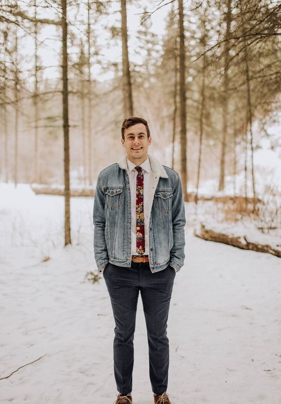 grey pants, amber boots, a white shirt, a floral tie and a denim jacket with faux fur for a relaxed woodland wedding