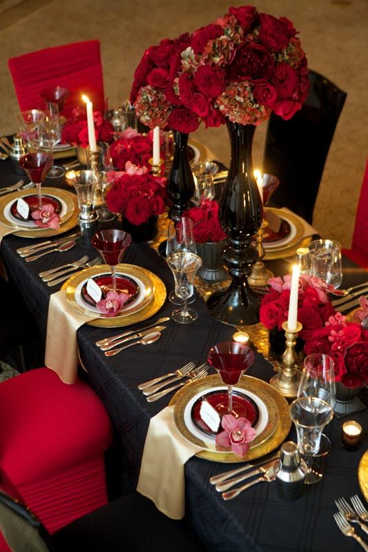 A Gothic wedding tablescape done in black, red and gold, with candles, red glasses and lush florals