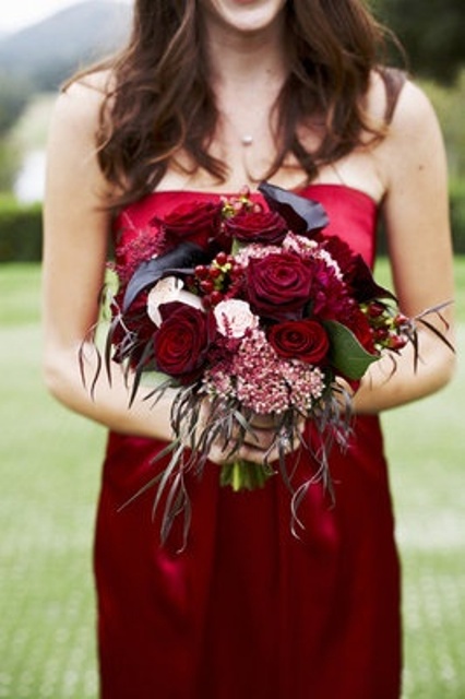 a bridesmaid bouquet with black callas and red blooms plus soem textural leaves