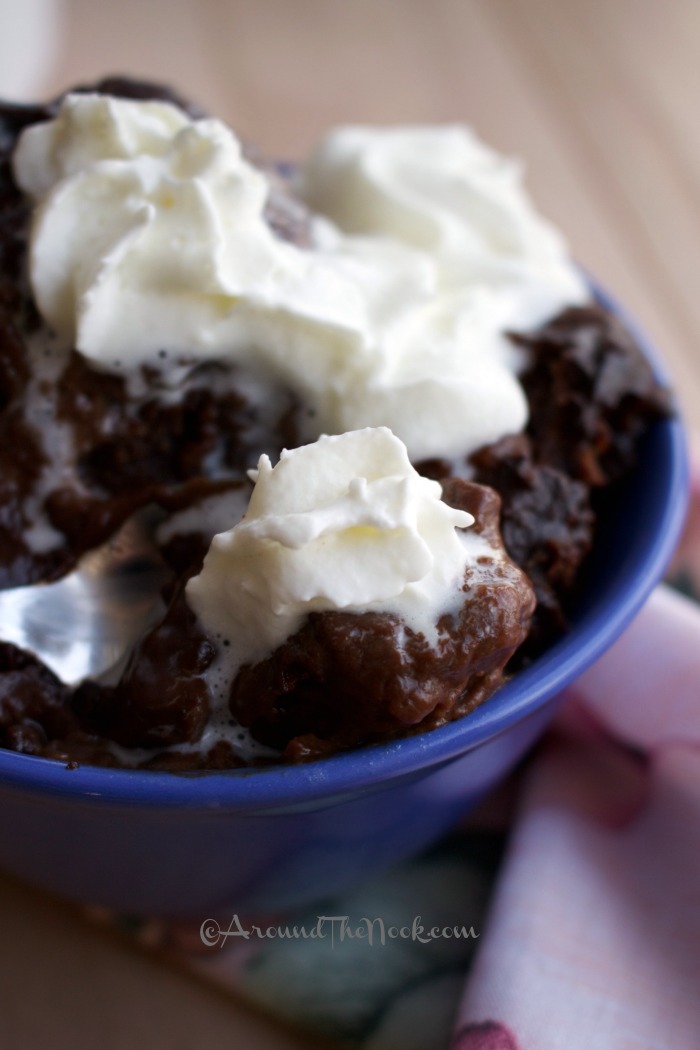 A blue bowl filled with chocolate pudding cake recipe topped with whipped cream