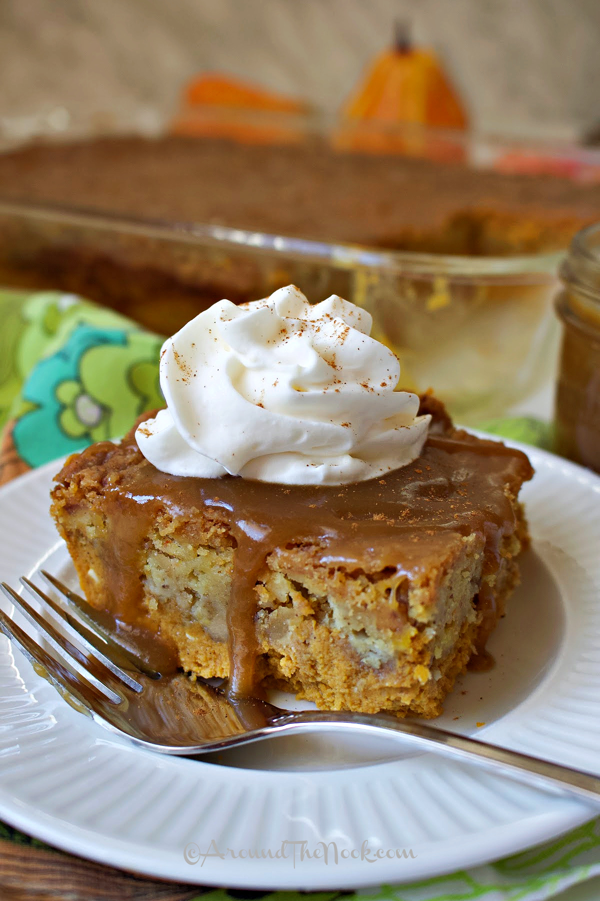 Pumpkin Pie Dump Cake on a white plate with caramel drizzle and whipped cream.