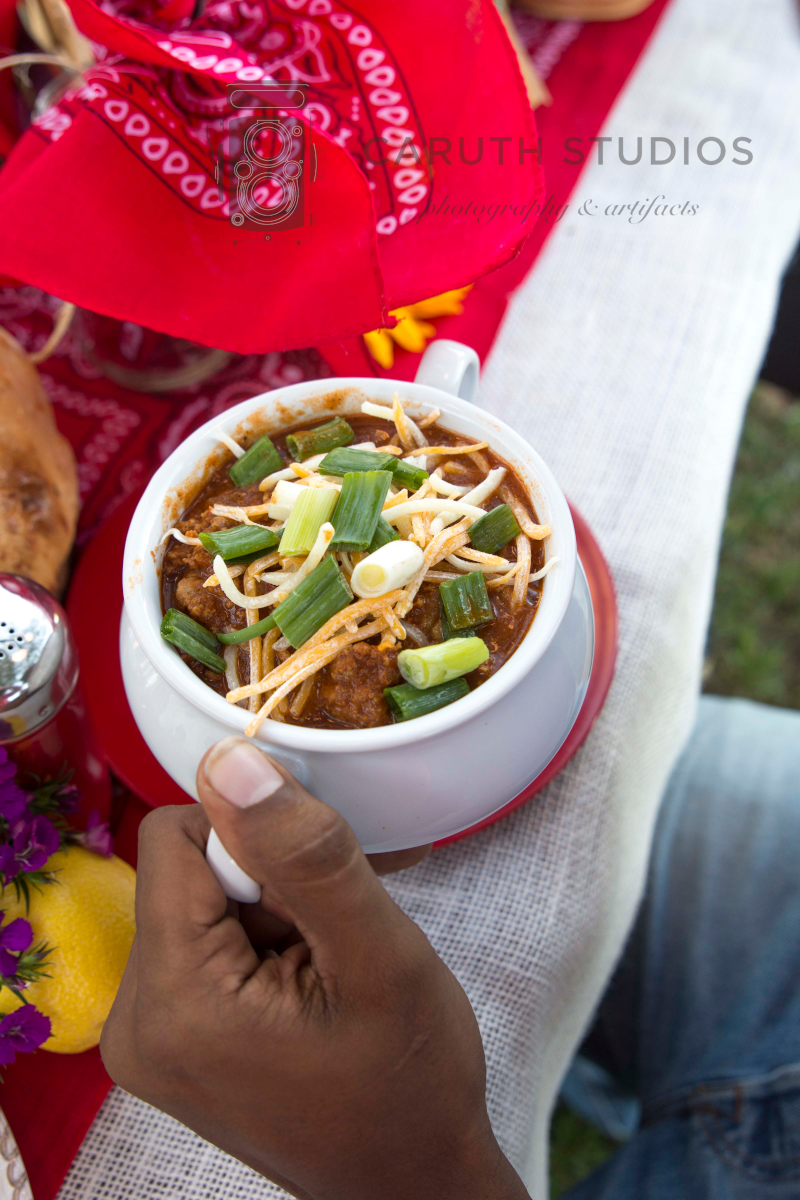 bowl of chili topped with cheese, green onion and sour cream