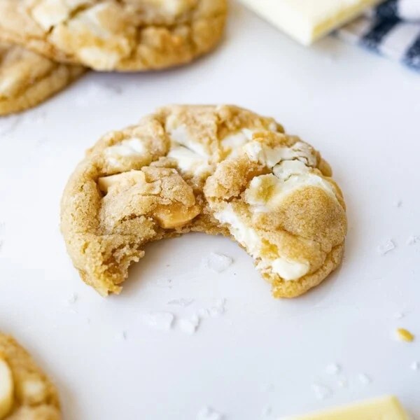 white chocolate macadamia nut cookie on the counter with a bite taken out of it.