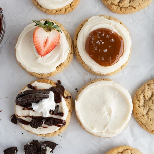 A grid of cheesecake cookies topped with different toppings on the counter.