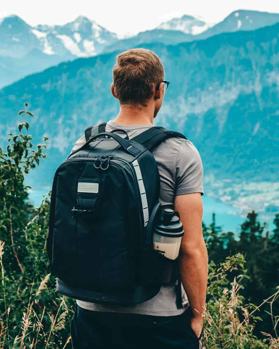 Man standing in the swiss alps looking out wearing the PolarPro backpack, the best camera backpack