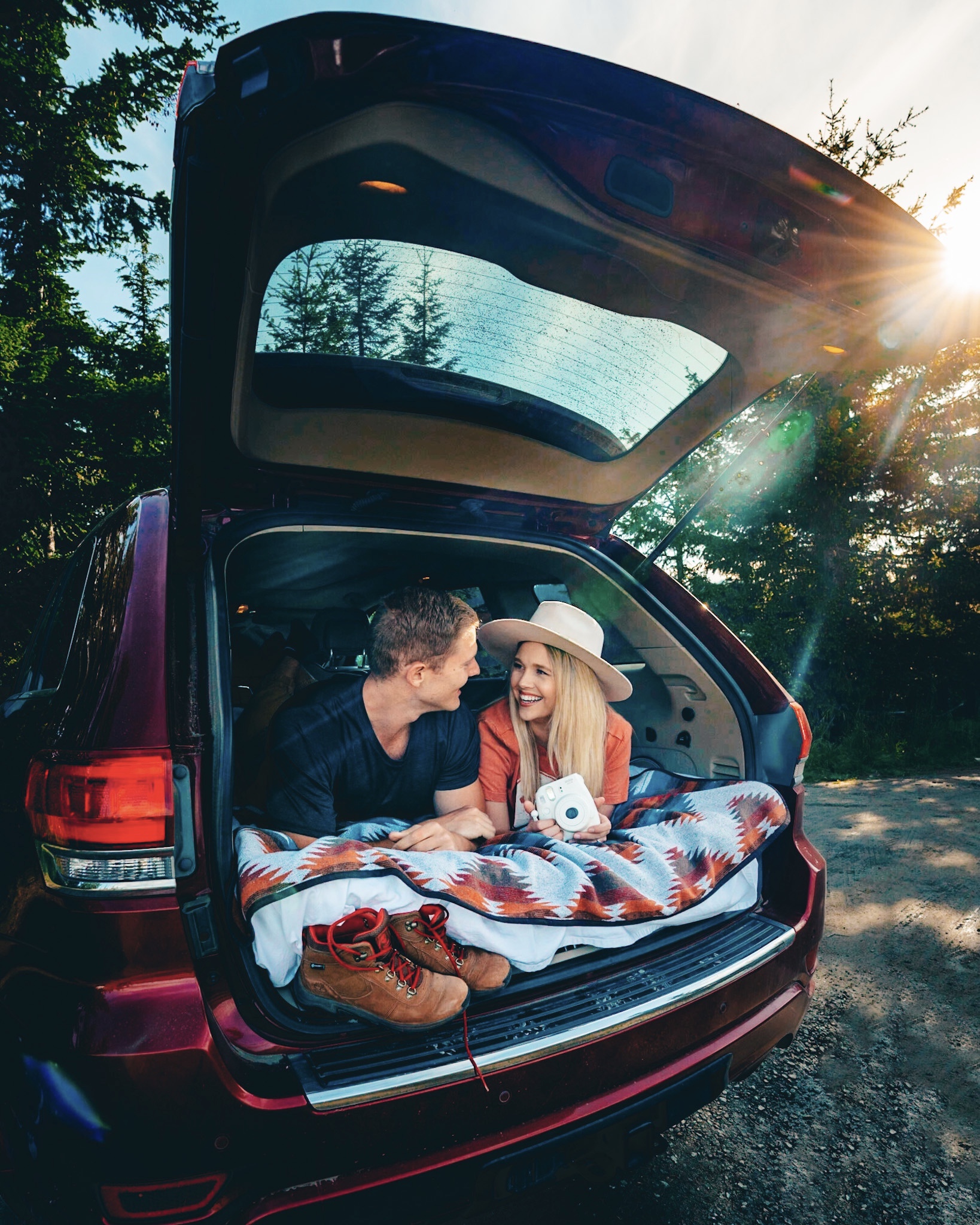 Smiling and looking at each other inside the trunk of the car while car camping