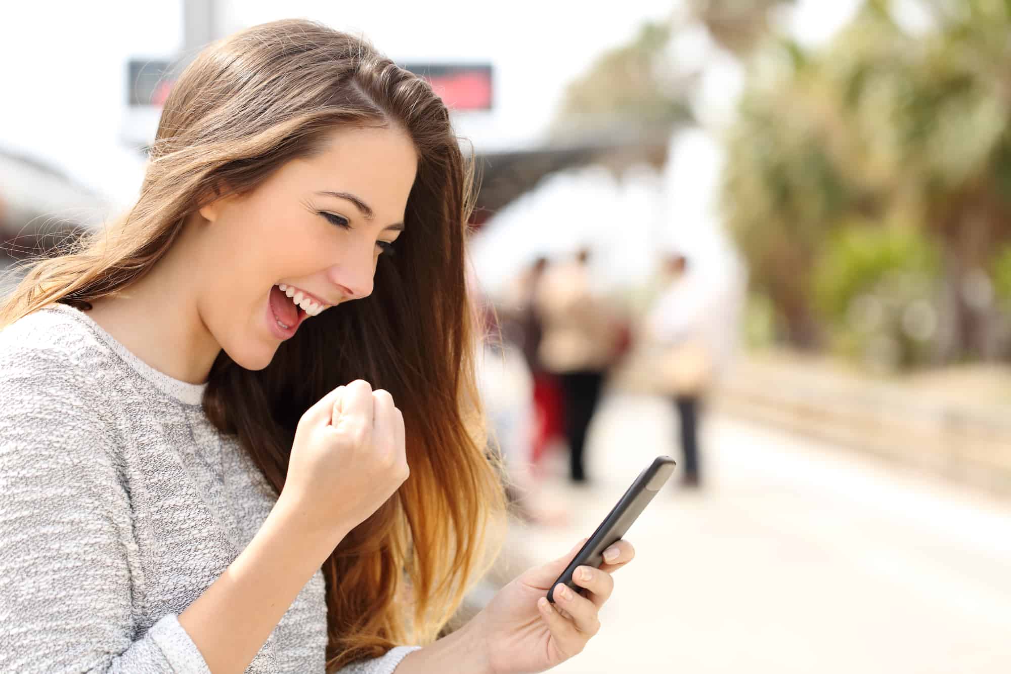 Woman using her smart phone to earn money by referring friends to her favorite programs.