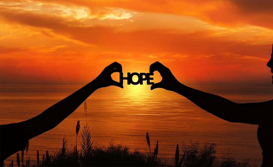 Beach sunset, with hands holding up the word 'HOPE'