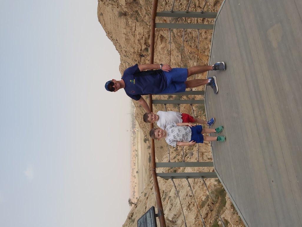 Dad and boys smiling on a family hike in UAE.