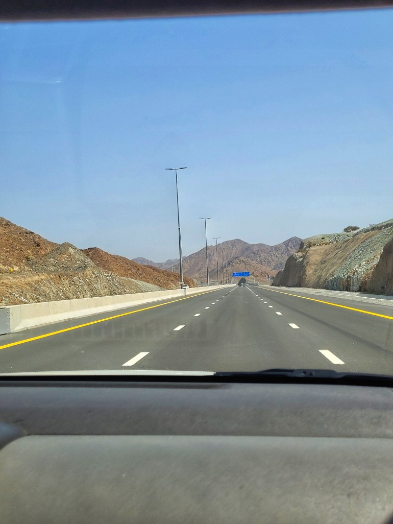 A long straight road driving through mountains on the way to a weekend in Muscat. 