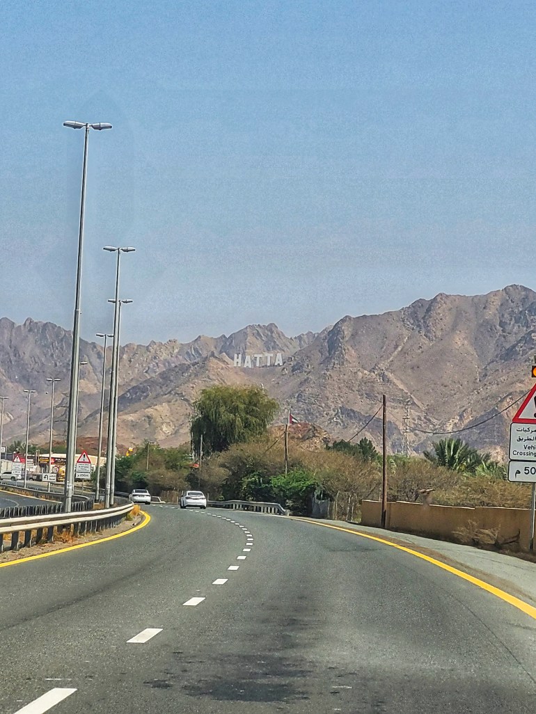 A road with Hatta mountains and sign in the background. On the way for a weekend in Muscat. 