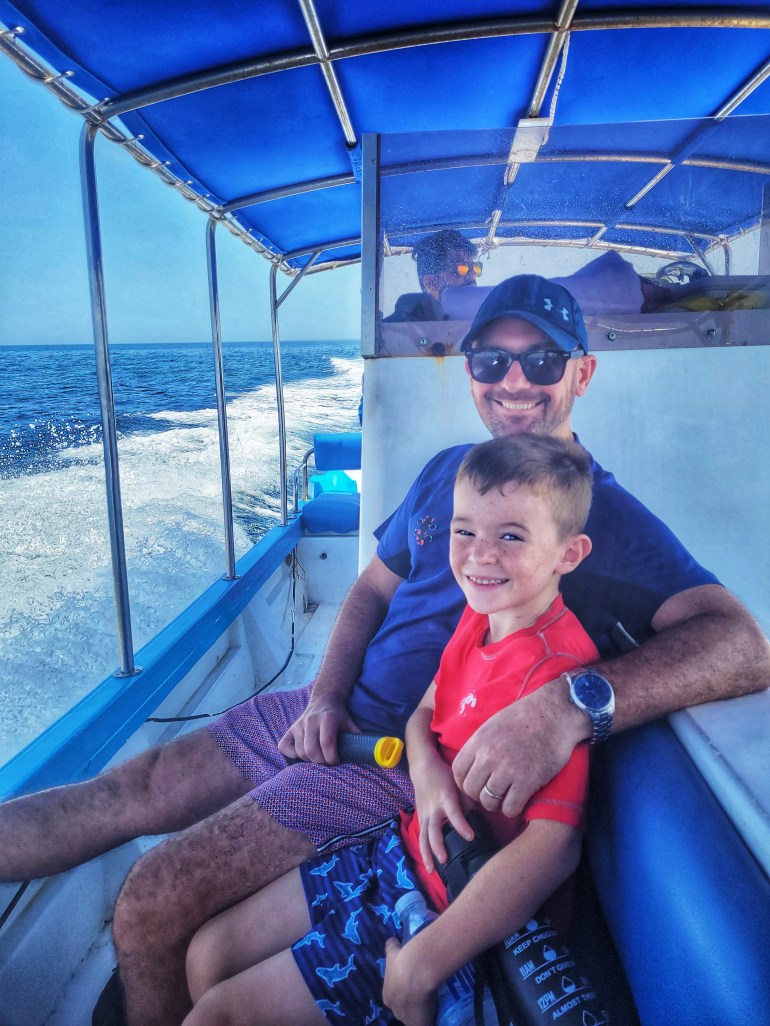 Dad and boat smiling sitting on a boat looking for dolphins on a weekend in Muscat. 