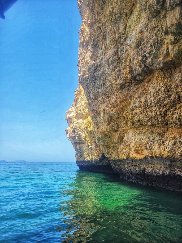 A cliff on beautiful blue and green sea. A boat trip is a must on a weekend in Muscat. 