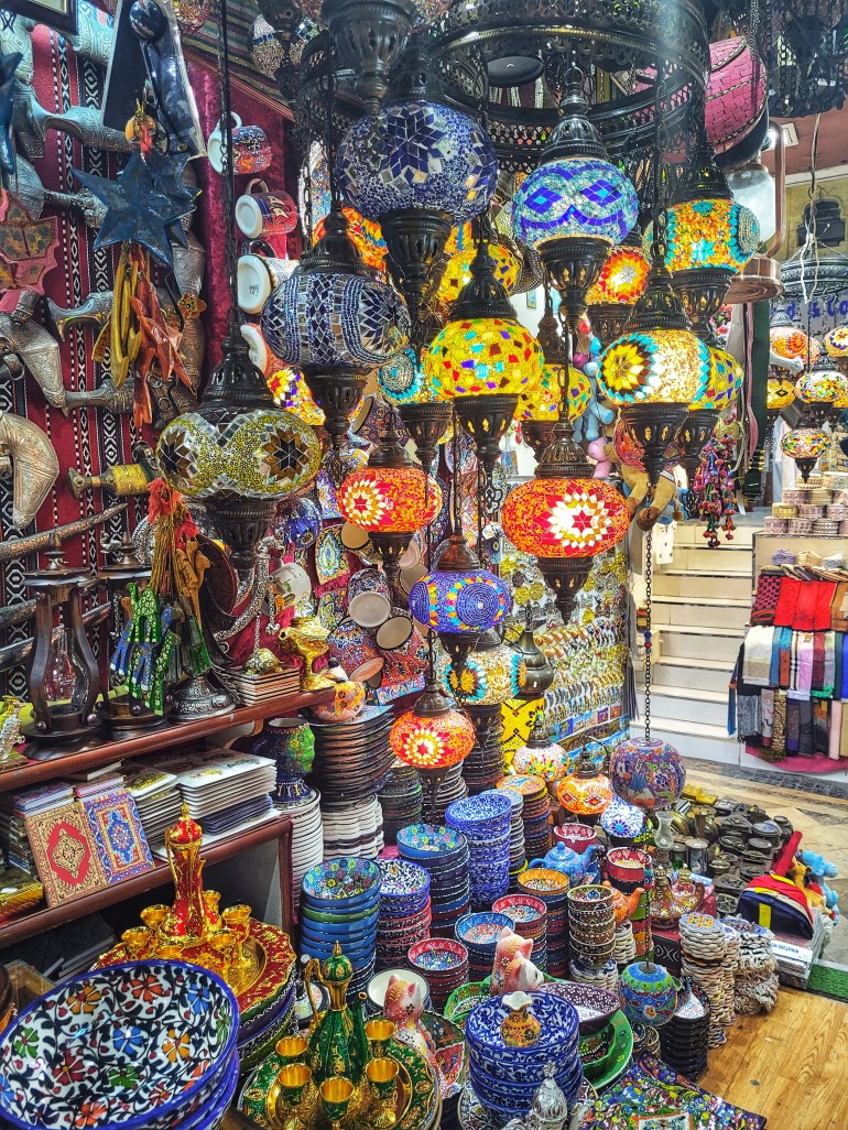 Lanterns and colourful bowls and crockery in a souq. 