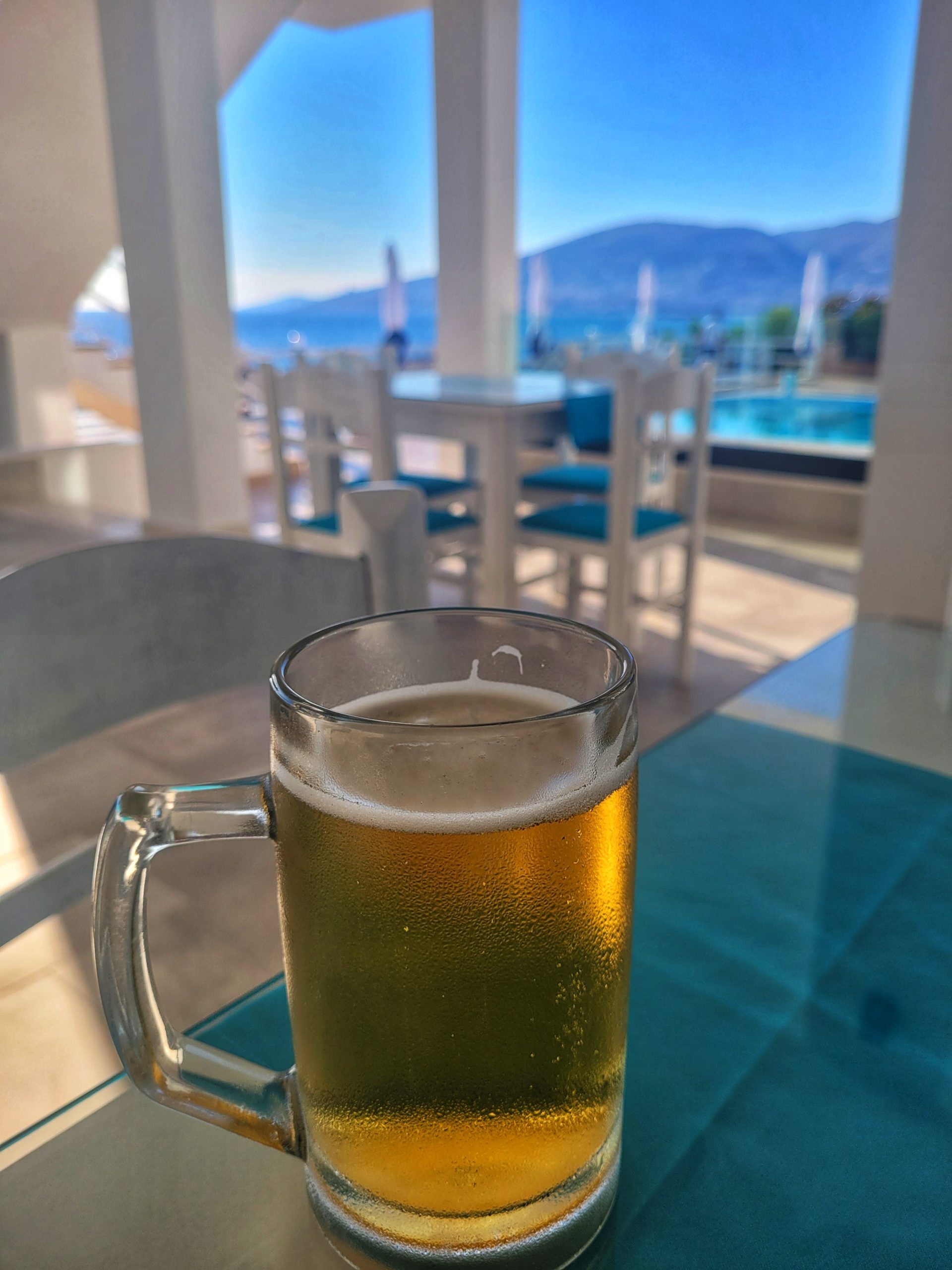 A draught beer with a view of the pool and ocean in the background. 