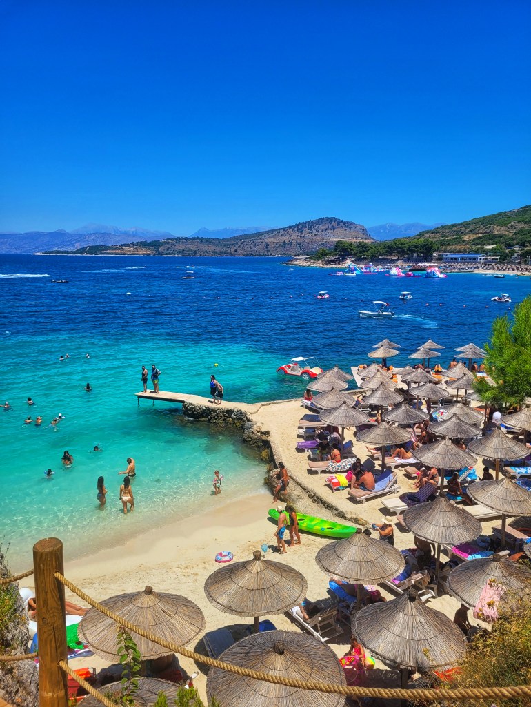 A beautiful birds eye view of a sandy beach in Ksamil with sun umbrellas. Vising Ksamil when you travel to Albania.