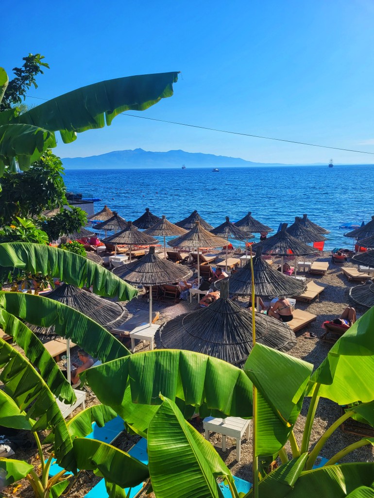 A view of beach umbrellas overlooking the bright blue sea. Saranda is a must stop on your holiday to Albania. 