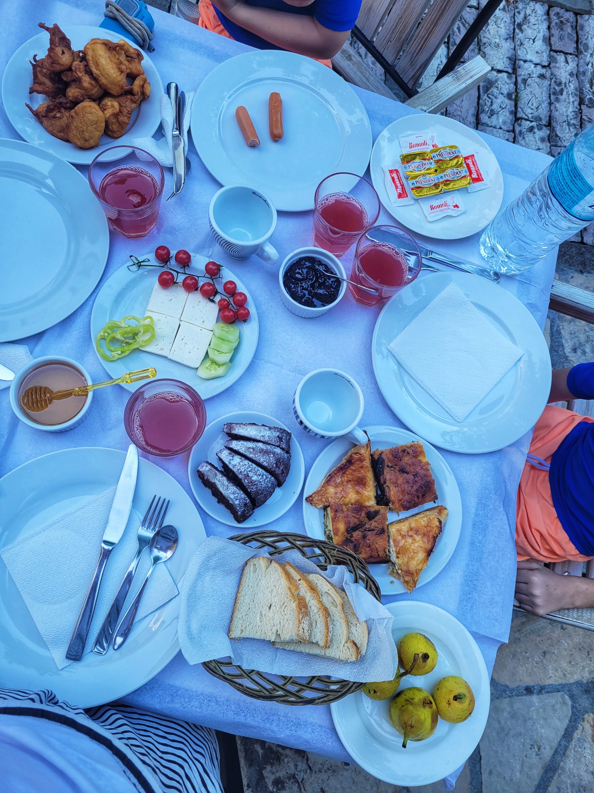 A birds eye view of a breakfast table with pears, byrek, bread, cake, juice, feta, honey. Typical breakfast on a holiday in Albania.