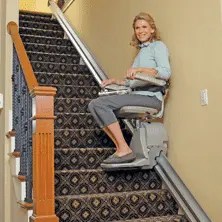 A woman using a straight stair lift.