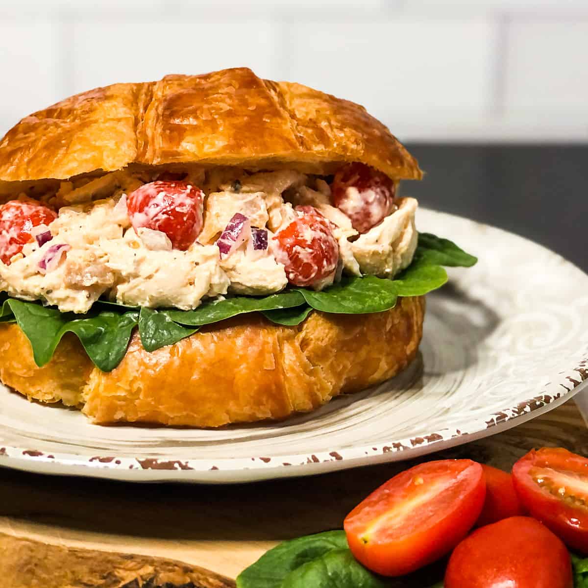 BLT Chicken Salad in a croissant on a neutral plate.