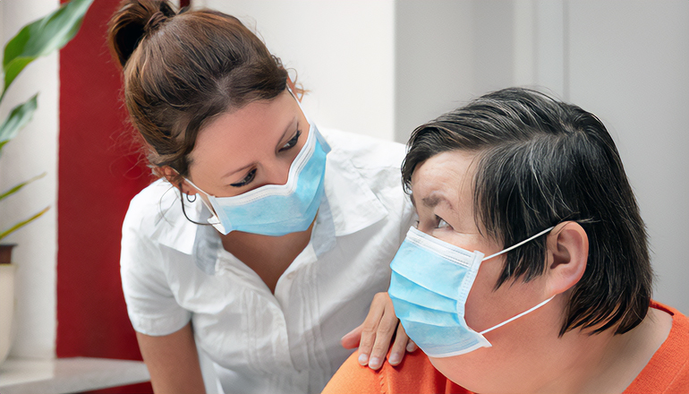 Mentally disabled woman and nurse or caretaker wearing a surgica