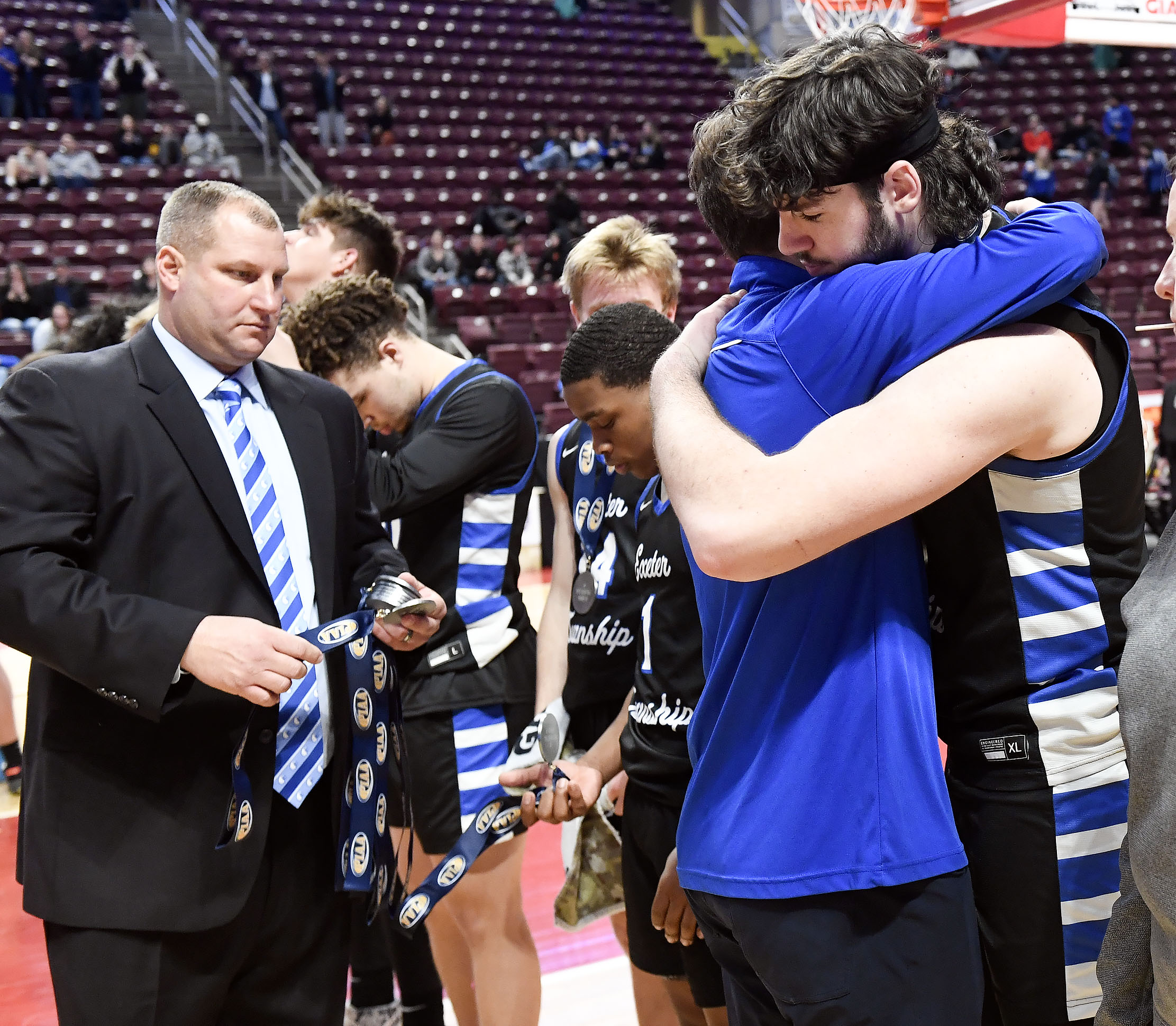 Exeter head coach Matt Ashcroft embraces Anthony Caccese following their PIAA Class 5A boys basketball loss to Imhotep Charter Friday at the Giant Center in Hershey. (BILL UHRICH - READING EAGLE)