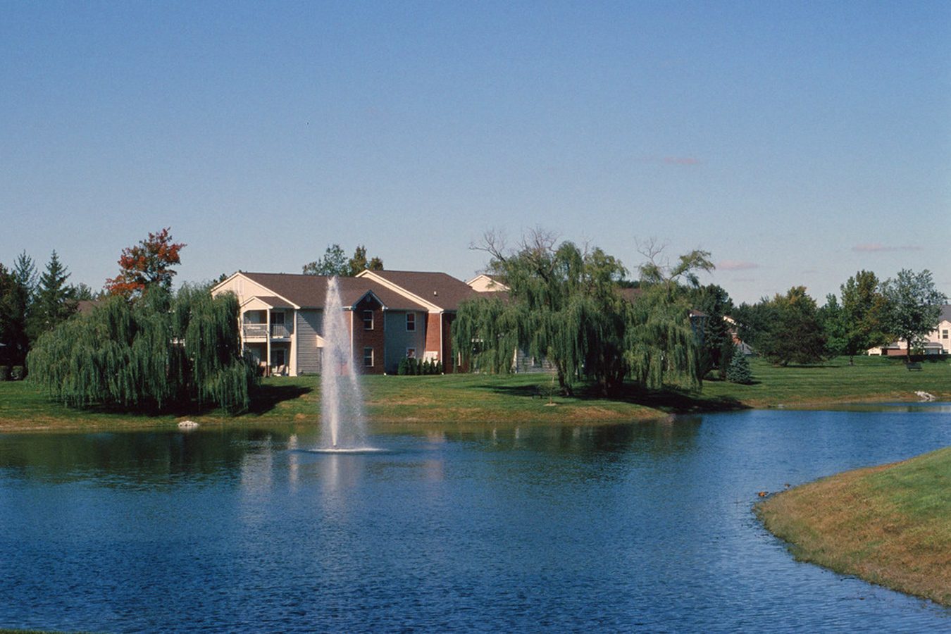 Apartment buildings by tranquil pond.