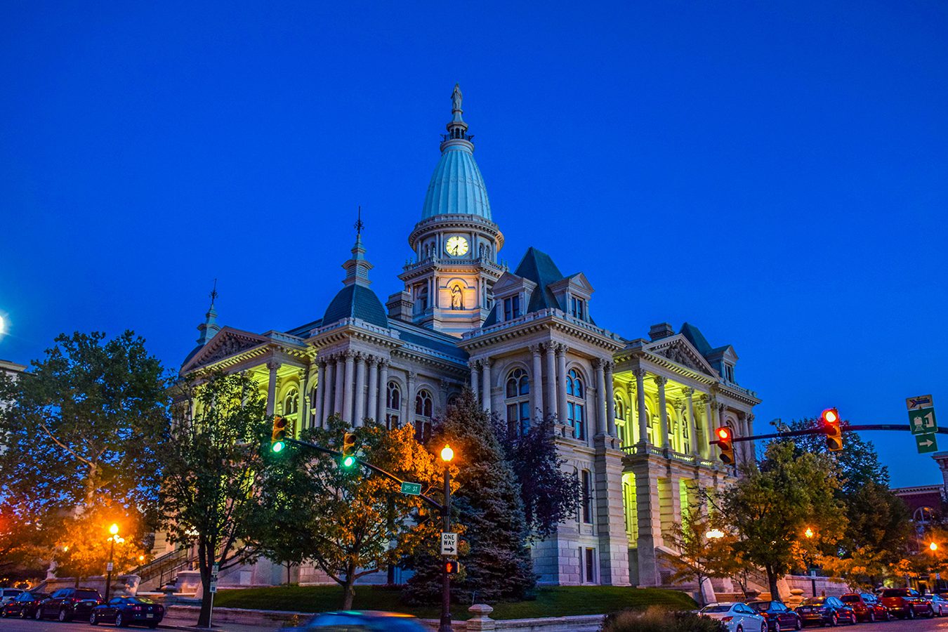 Here's an 8-word alt tag for the image: Illuminated courthouse at twilight, city street scene.