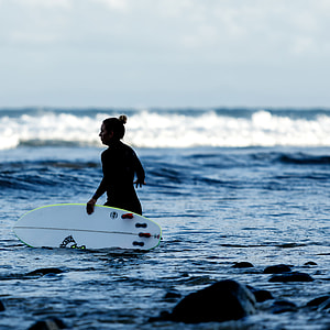 Royalty-Free photo: Woman wears bikini holds surfboard at daytime in ...