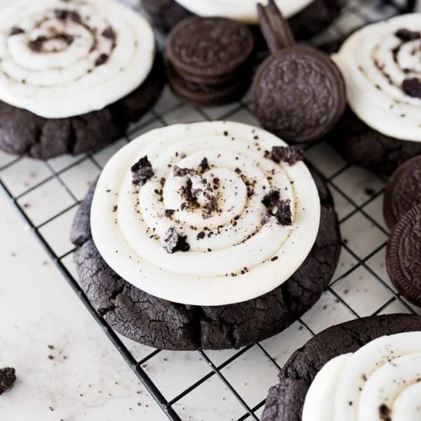 Crumbl copycat Oreo cookie on a black cooling rack with Oreos in the back ground