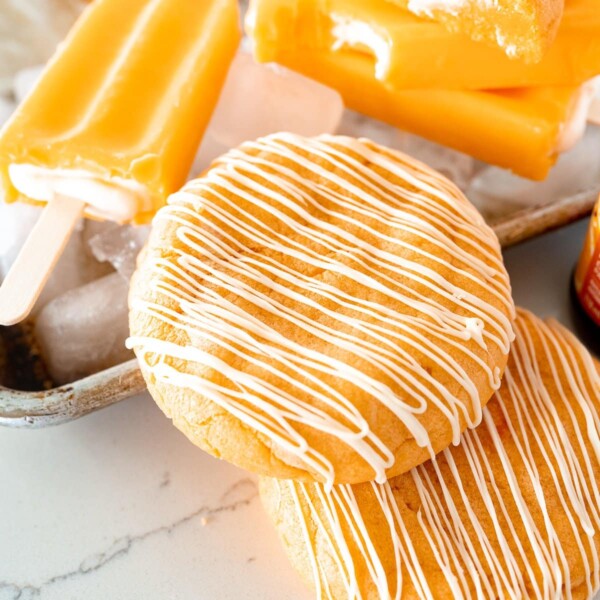 Orange creamsicle cookies on the counter next to a popsicle