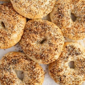 A pile of everything bagels on the counter.