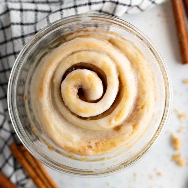 A single serve cinnamon roll in a glass dish.