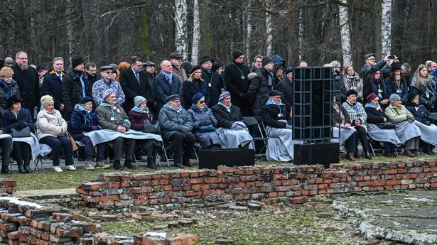 Survivors take part in a collective pray at the Ruins of gas chamber and crematorium