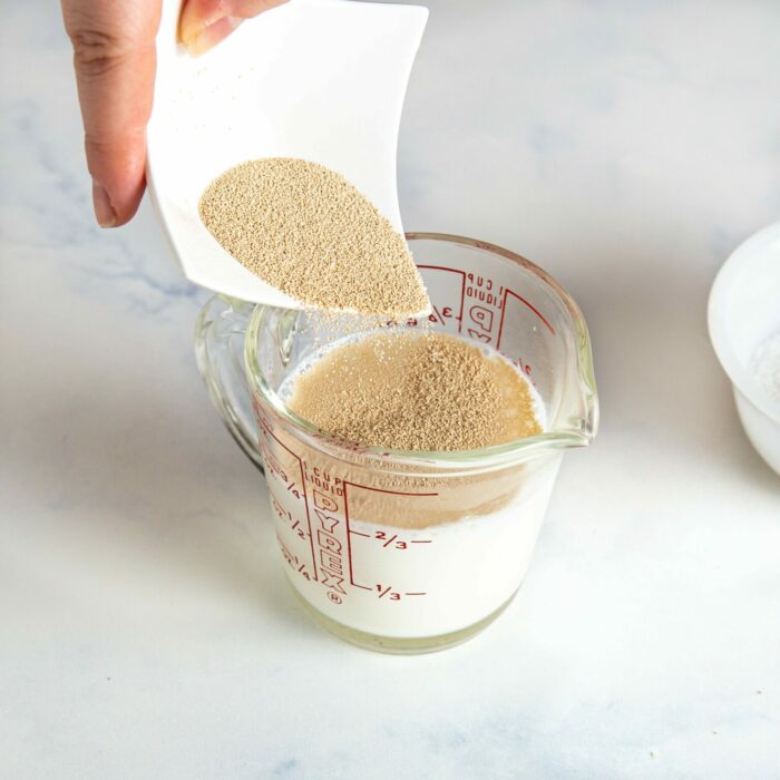 dried yeast being added to a glass of warm milk