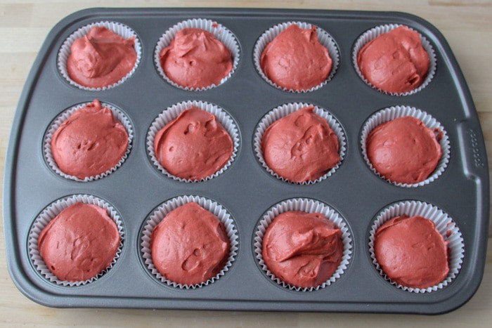 Cupcake pan filled with cupcake liners and filled with batter about level to the pan