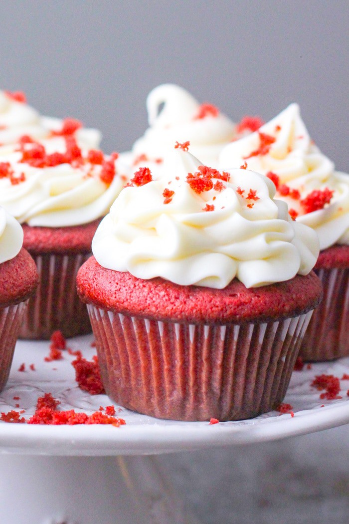 Red velvet cupcakes on a plate beautifully decorated with cream cheese frosting