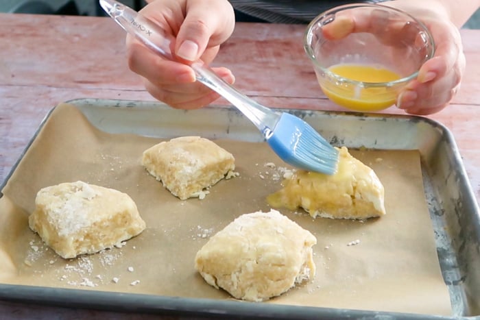 Brushing egg wash on a pan of scones with a pastry brush