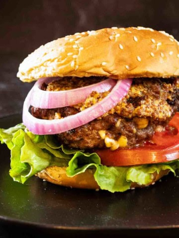 Black and blue burger with red onion, tomato and lettuce.